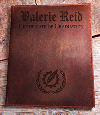 Brown leather certificate holder with 'Valerie Reid Certificate of Graduation' text and emblem on a wooden surface.