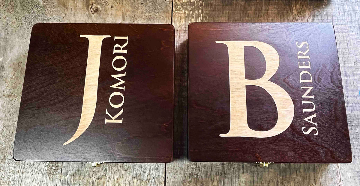 Two wooden blocks with engraved initials and names on a wooden surface