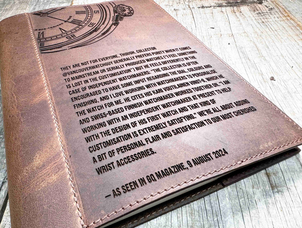 A brown, custom-engraved leather notebook cover featuring a geometric unicorn head design. The notebook is resting on an antique-style, ornate wooden desk alongside a glass inkwell and a feathered quill pen, creating a sophisticated and vintage aesthetic.