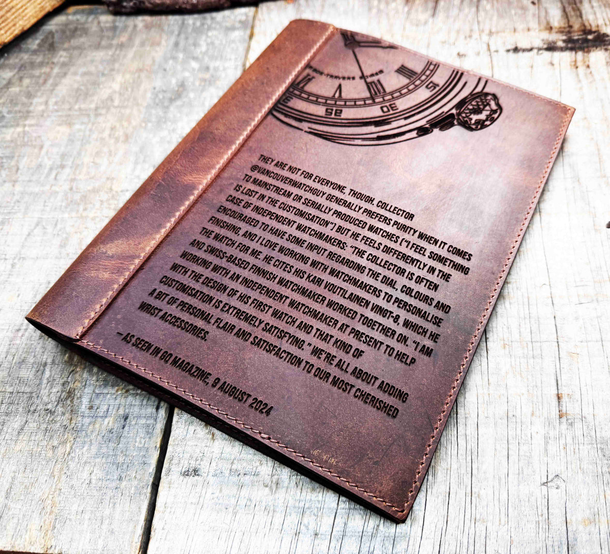 A brown, custom-engraved leather notebook cover featuring a geometric unicorn head design. The notebook is resting on an antique-style, ornate wooden desk alongside a glass inkwell and a feathered quill pen, creating a sophisticated and vintage aesthetic.