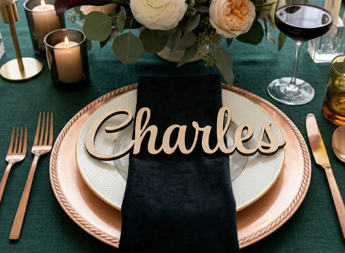 Table setting with 'Charles' name card on a decorative plate with candles and wine glass in the background.