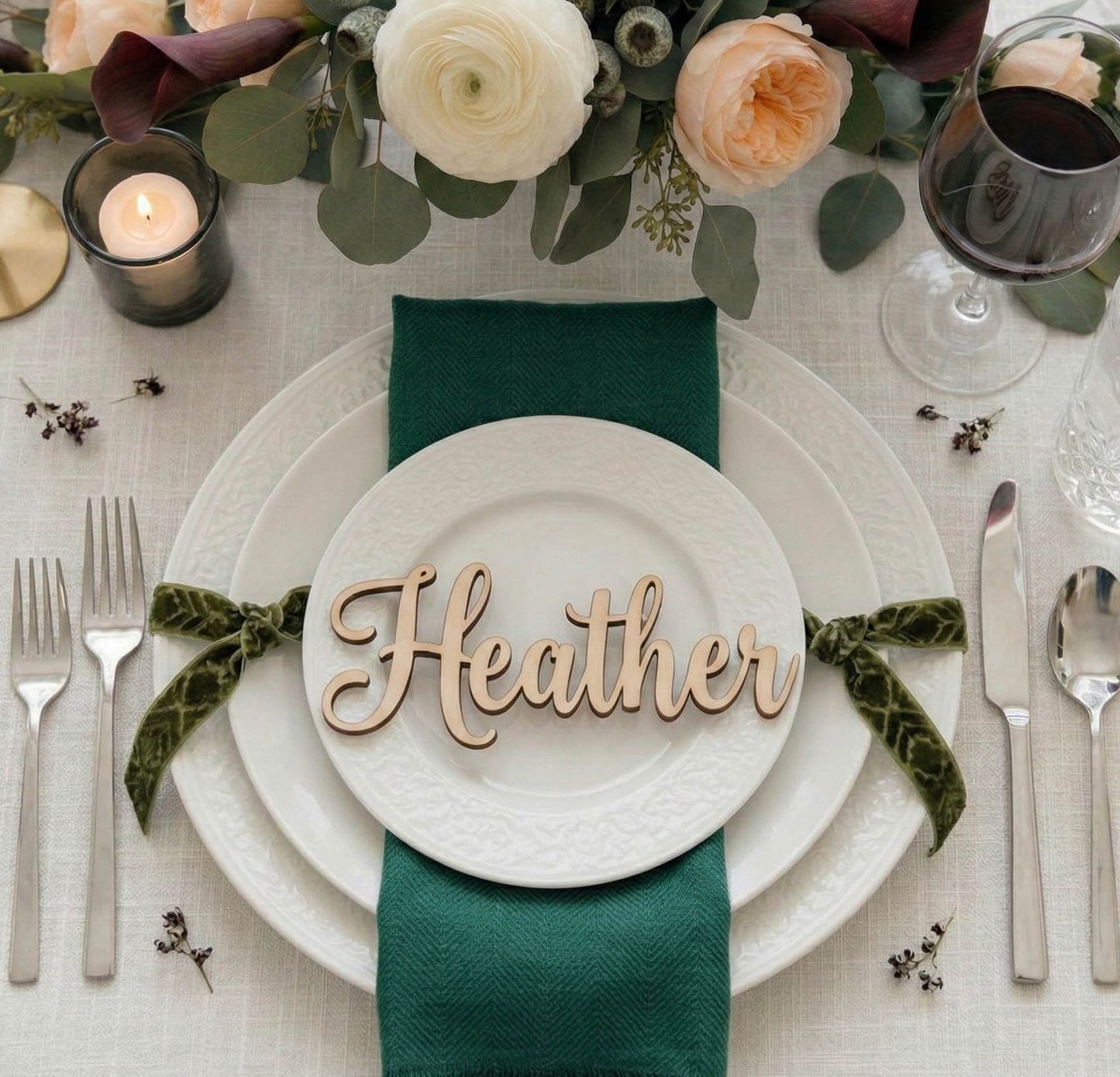 Table setting with 'Heather' name card, green napkin, and floral decorations.